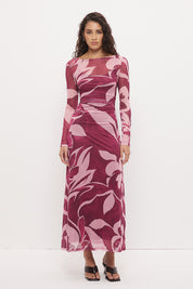 Woman wearing a sheer maxi dress with an exclusive placement print, fit-and-flare silhouette, flared long sleeves, ruched waistline, and a separate full-length slip.