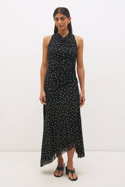 Woman wearing a printed polka dot mesh sleeveless midi dress with a draped cowl neckline, fit-and-flare silhouette, ruched drawcord waist, and asymmetric hi-lo raw-cut hem.
