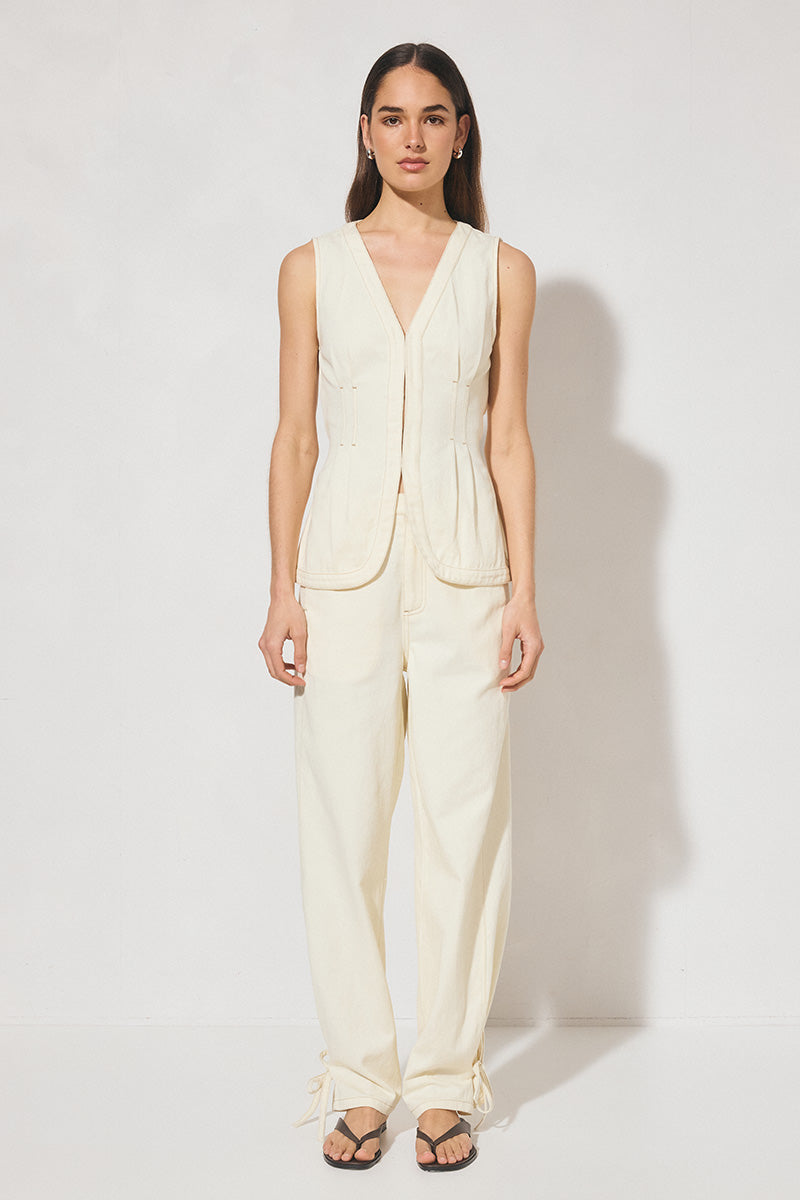 Sleeveless denim longline vest top with V neckline, pintucked waist, back tie, curved front hem, banded edges, and contrast topstitching