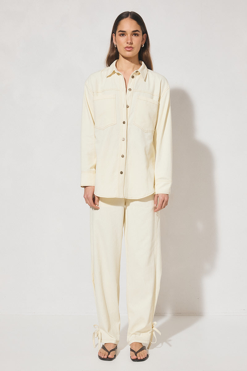 Long-sleeved oversized denim shirt with dropped shoulders, collar & stand, back box-pleat, back waist tie, chest patch pockets, side hem splits, and contrast topstitching