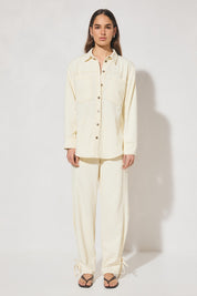 Long-sleeved oversized denim shirt with dropped shoulders, collar & stand, back box-pleat, back waist tie, chest patch pockets, side hem splits, and contrast topstitching