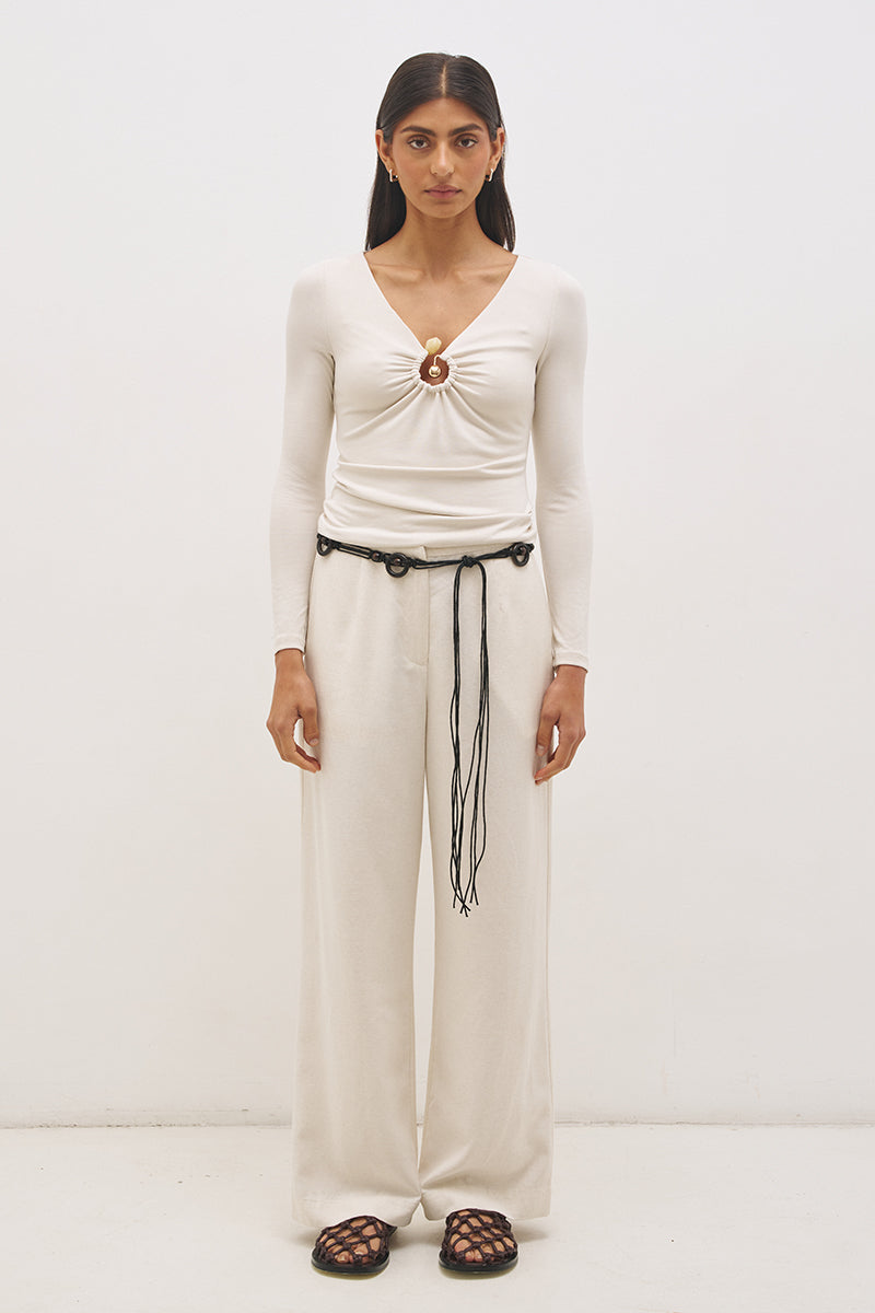 Woman wearing jersey knit long sleeve top with spiral ring neckline, plunging V neck, cascading ruching, and skimming fit silhouette