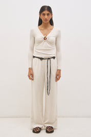 Woman wearing jersey knit long sleeve top with spiral ring neckline, plunging V neck, cascading ruching, and skimming fit silhouette