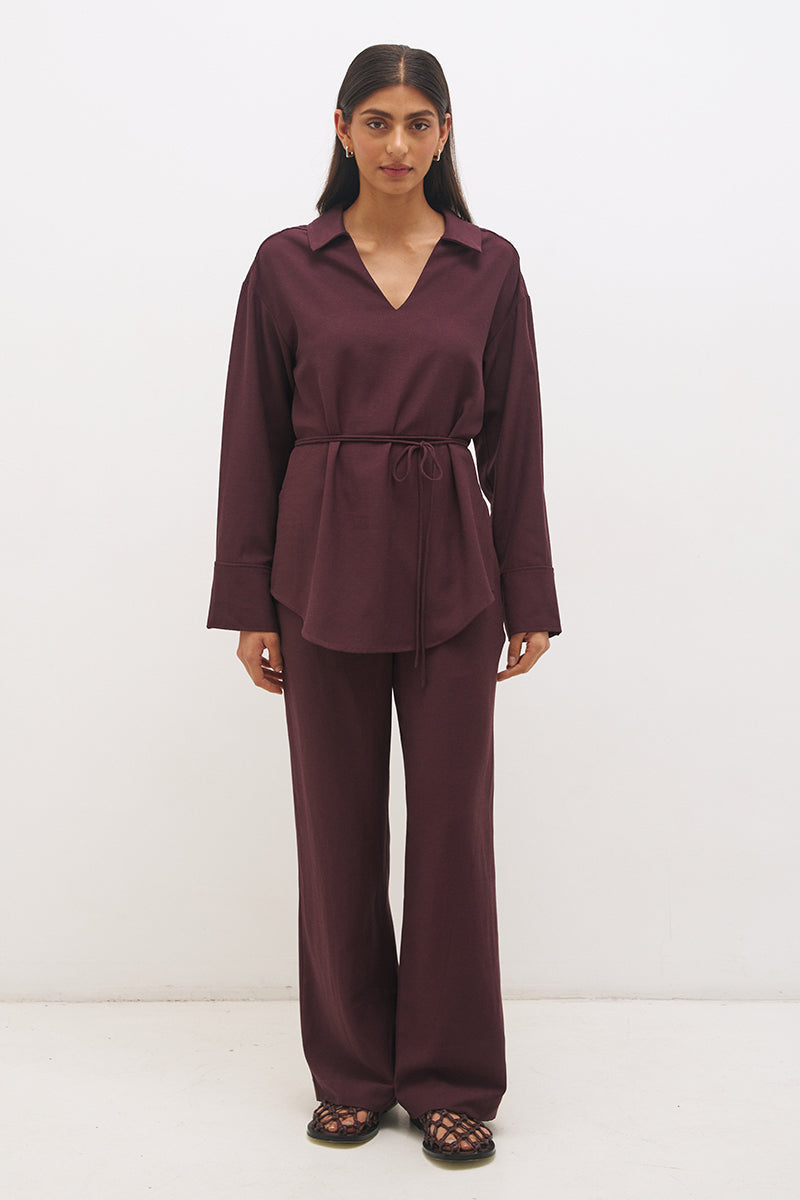Woman wearing a satin-backed linen blend longline tunic with V neckline, curved hem, relaxed fit, and removable waist tie