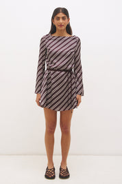 Woman wearing an asymmetric stripe satin mini dress with boat neckline, flared sleeves, flared hem, and removable waist tie