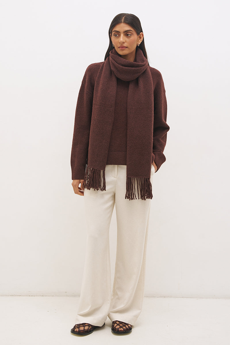 Woman wearing oversized scarf knit jumper with removable tassel scarf, crew neckline, ribbed trims, and relaxed silhouette