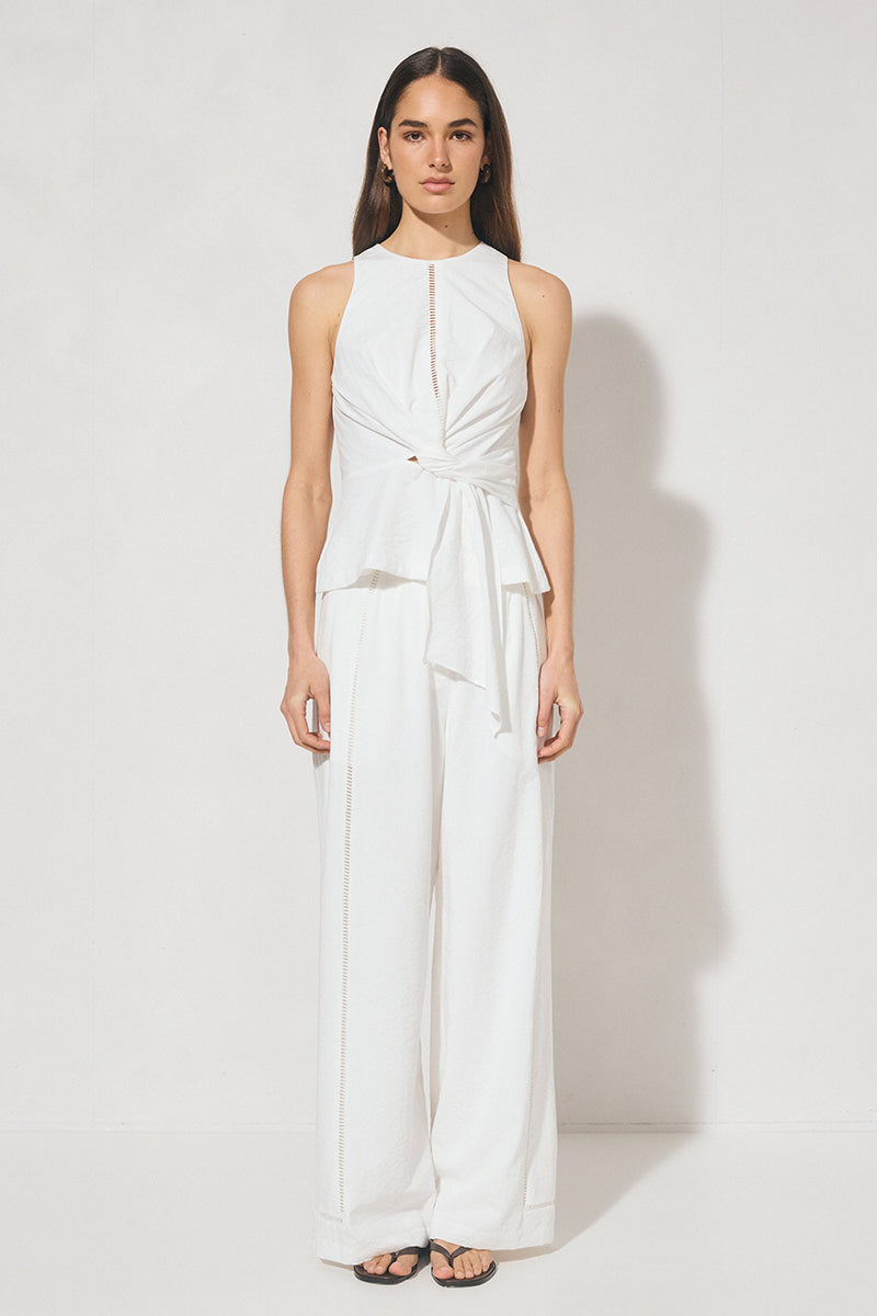 Sleeveless textured woven top with crew neckline, ladder trim detail, twisted waist sash, and side seam splits