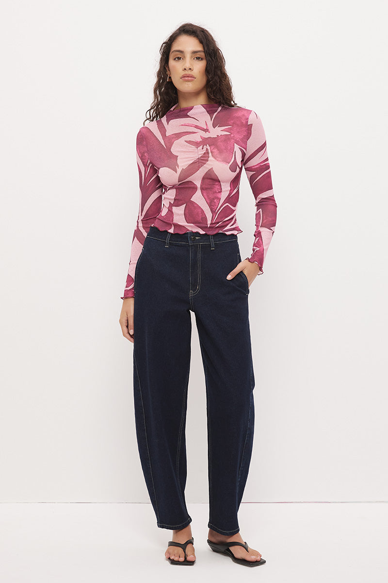 Woman wearing a semi-sheer long sleeve top in stretch ribbed mesh with an exclusive placement print, funnel neckline, centre front chest ruching, and lettuce hem finishes.