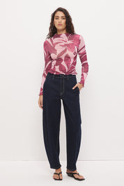 Woman wearing a semi-sheer long sleeve top in stretch ribbed mesh with an exclusive placement print, funnel neckline, centre front chest ruching, and lettuce hem finishes.