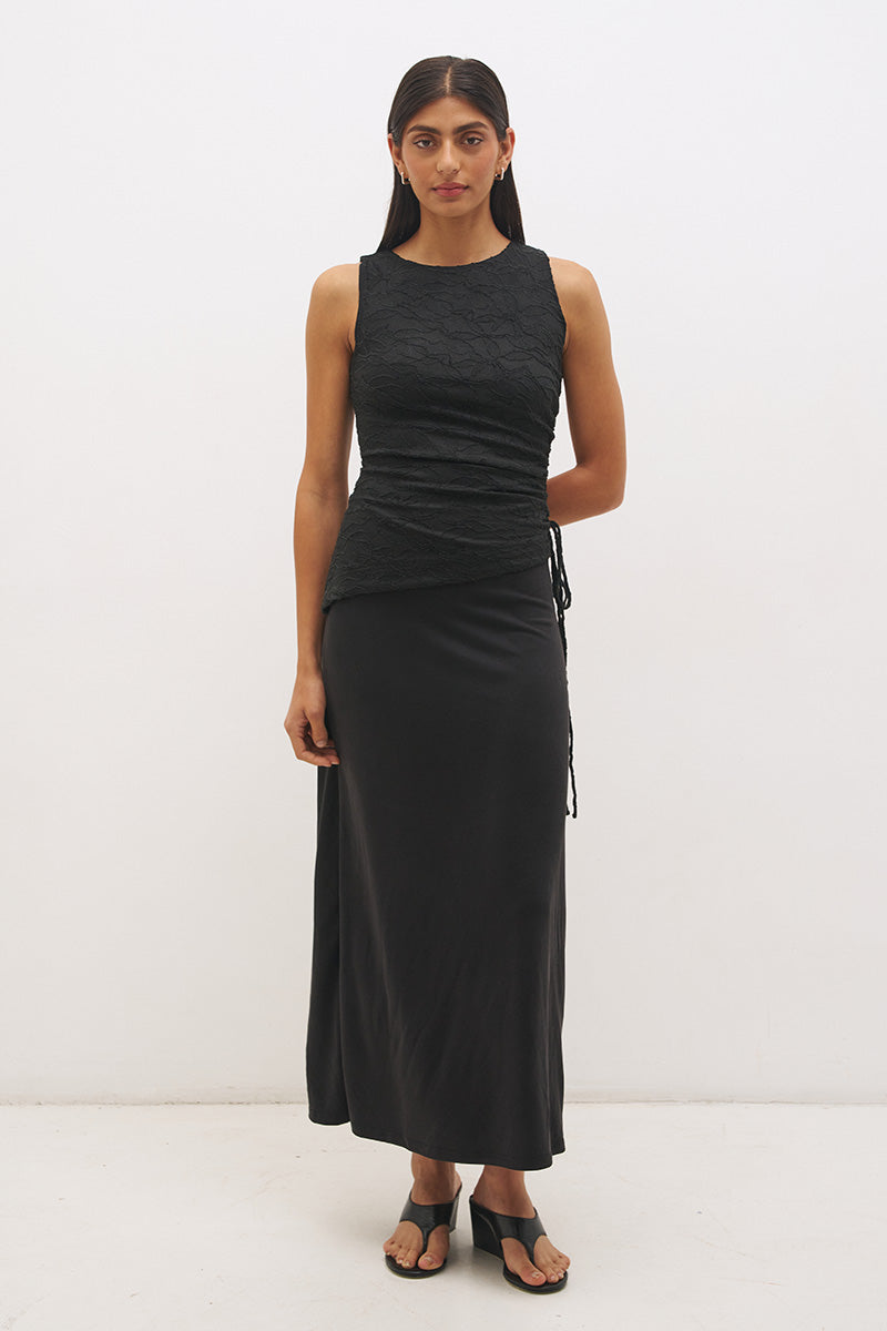 Woman wearing a sleeveless maxi dress with a textured lace bodice overlay, sunray ruching, boat neckline, and a contrast smooth A-line modal skirt in a fit-and-flare silhouette.