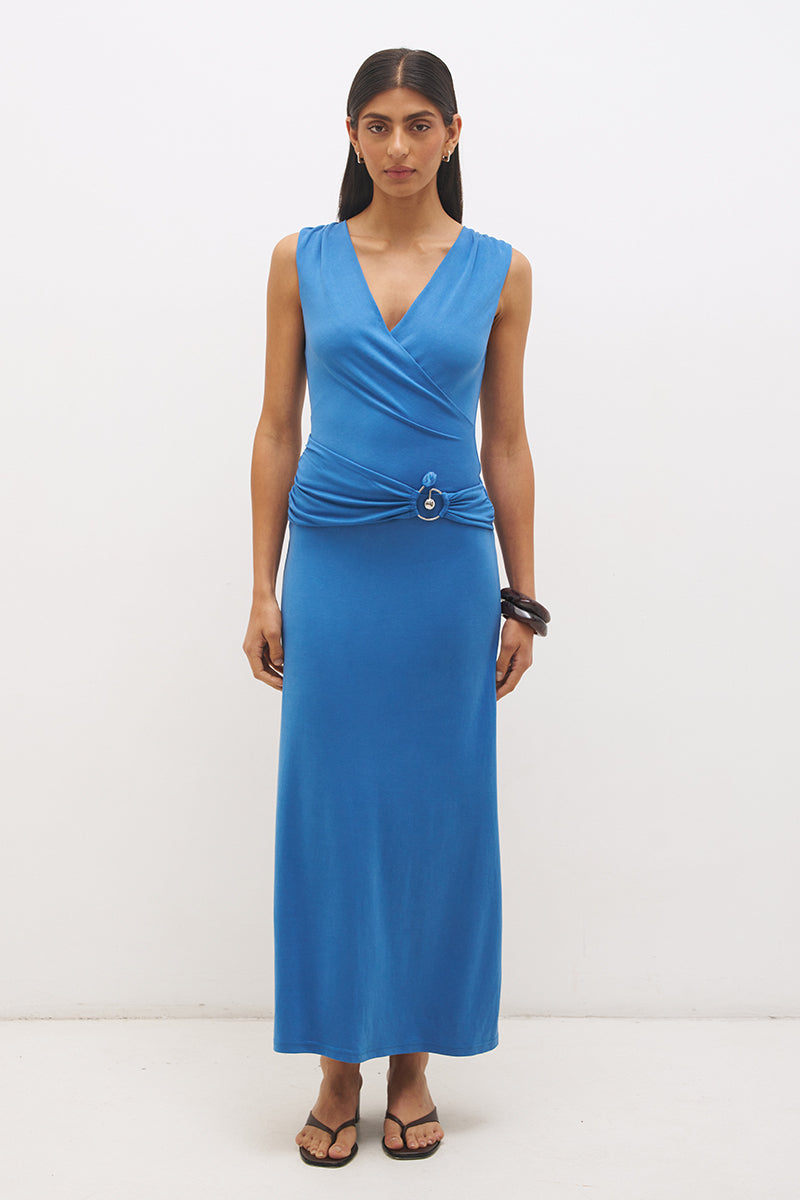 Woman wearing sleeveless jersey knit maxi dress with cowl neckline, spiral ring waist detail, cascading ruching, and fit-and-flare silhouette