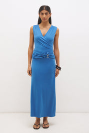 Woman wearing sleeveless jersey knit maxi dress with cowl neckline, spiral ring waist detail, cascading ruching, and fit-and-flare silhouette