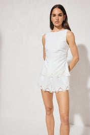 Sleeveless embroidered top with boat neckline, scooped back, functional waist tie, side splits, and relaxed fit