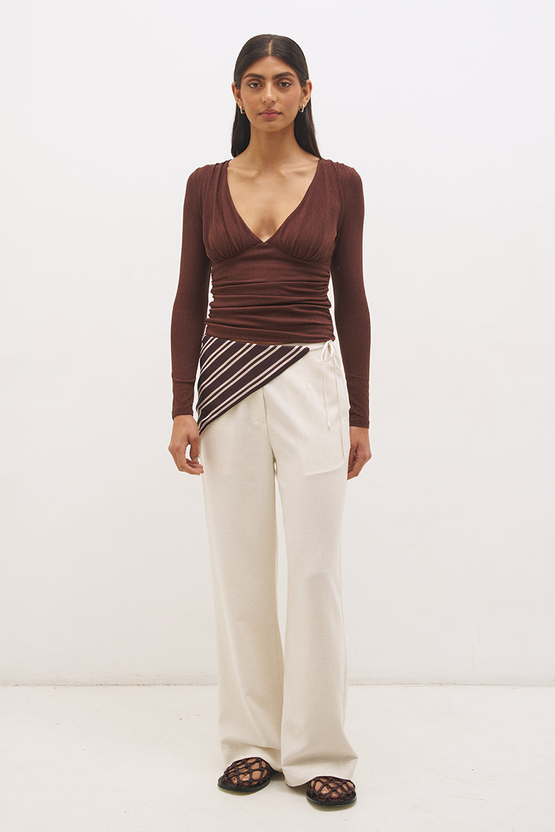 Woman wearing a textured cupro jersey long sleeve top with plunging V neckline, gathered bust detail, empire waist silhouette, and skimming fit