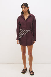 Woman wearing a satin-backed linen blend shirt dress with relaxed fit, collar neckline, curved hem, long sleeves, and removable scarf waist tie