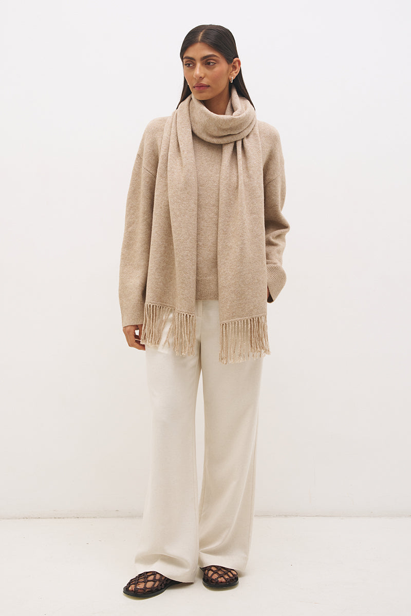 Woman wearing oversized scarf knit jumper with removable tassel scarf, crew neckline, ribbed trims, and relaxed silhouette