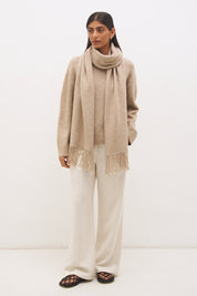 Woman wearing oversized scarf knit jumper with removable tassel scarf, crew neckline, ribbed trims, and relaxed silhouette