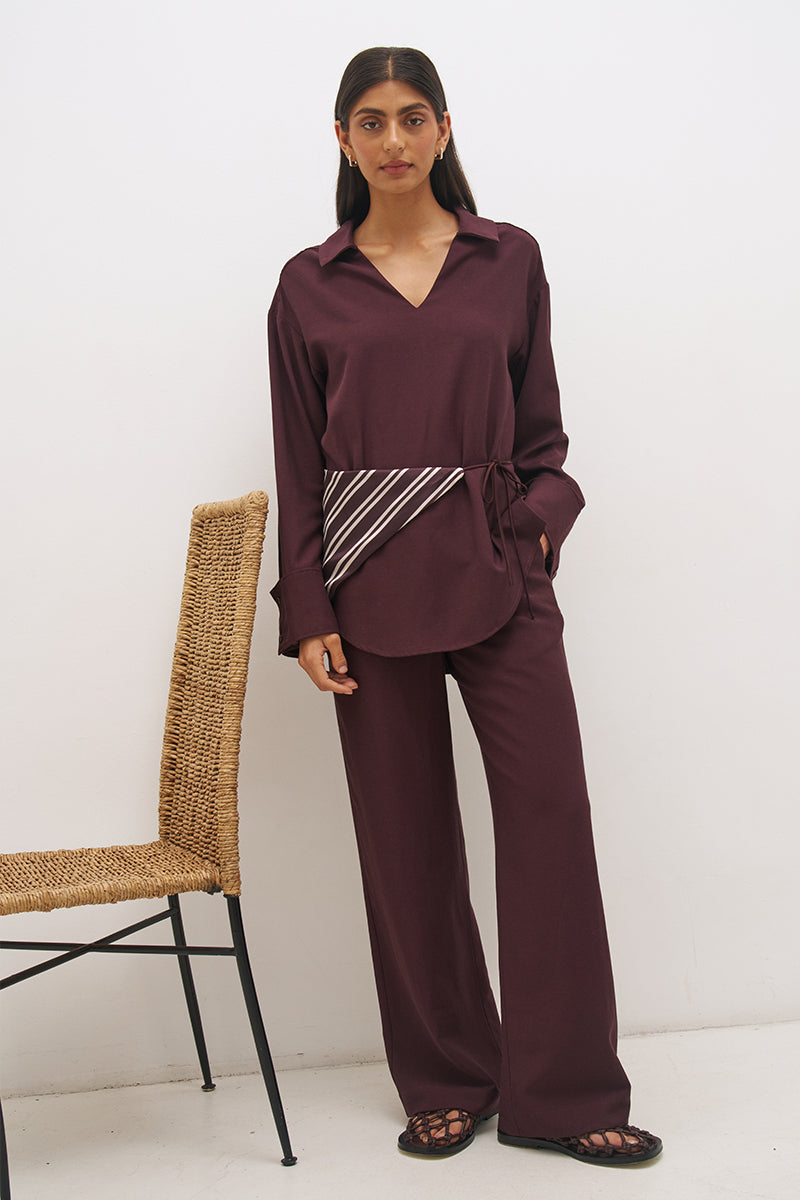 Woman wearing a satin-backed linen blend longline tunic with V neckline, curved hem, relaxed fit, and removable waist tie