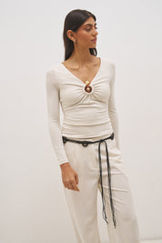 Woman wearing jersey knit long sleeve top with spiral ring neckline, plunging V neck, cascading ruching, and skimming fit silhouette