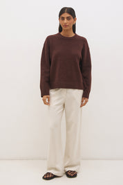 Woman wearing oversized scarf knit jumper with removable tassel scarf, crew neckline, ribbed trims, and relaxed silhouette