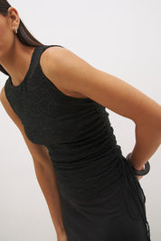 Woman wearing a sleeveless maxi dress with a textured lace bodice overlay, sunray ruching, boat neckline, and a contrast smooth A-line modal skirt in a fit-and-flare silhouette.