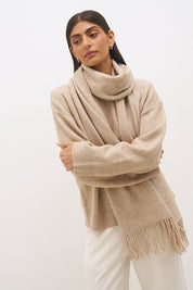 Woman wearing oversized scarf knit jumper with removable tassel scarf, crew neckline, ribbed trims, and relaxed silhouette