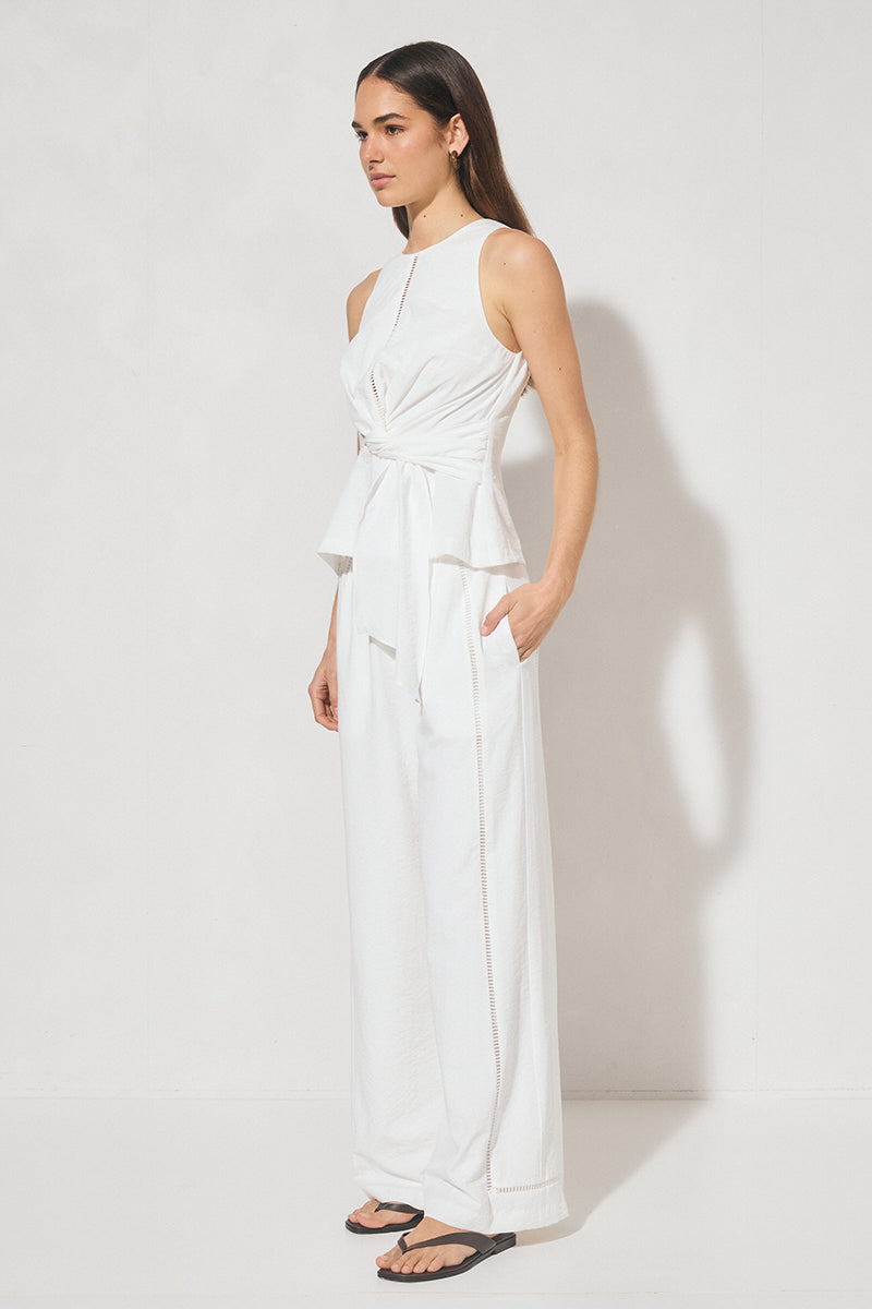 Sleeveless textured woven top with crew neckline, ladder trim detail, twisted waist sash, and side seam splits