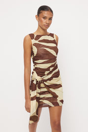 Sleeveless fitted mini dress with boat neckline, side ruching and sarong tie overlay in exclusive handcrafted print