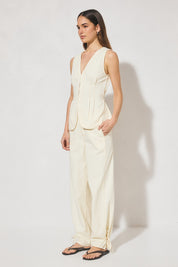 Sleeveless denim longline vest top with V neckline, pintucked waist, back tie, curved front hem, banded edges, and contrast topstitching