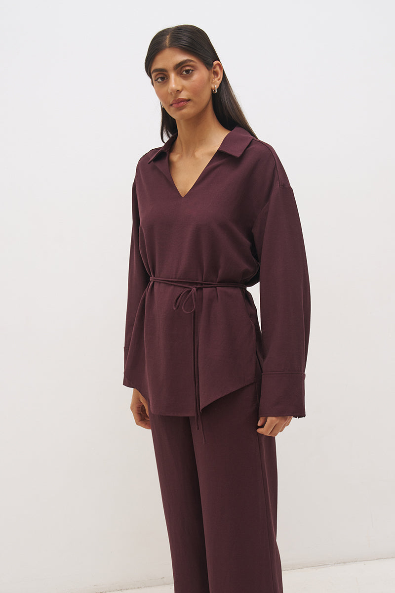 Woman wearing a satin-backed linen blend longline tunic with V neckline, curved hem, relaxed fit, and removable waist tie