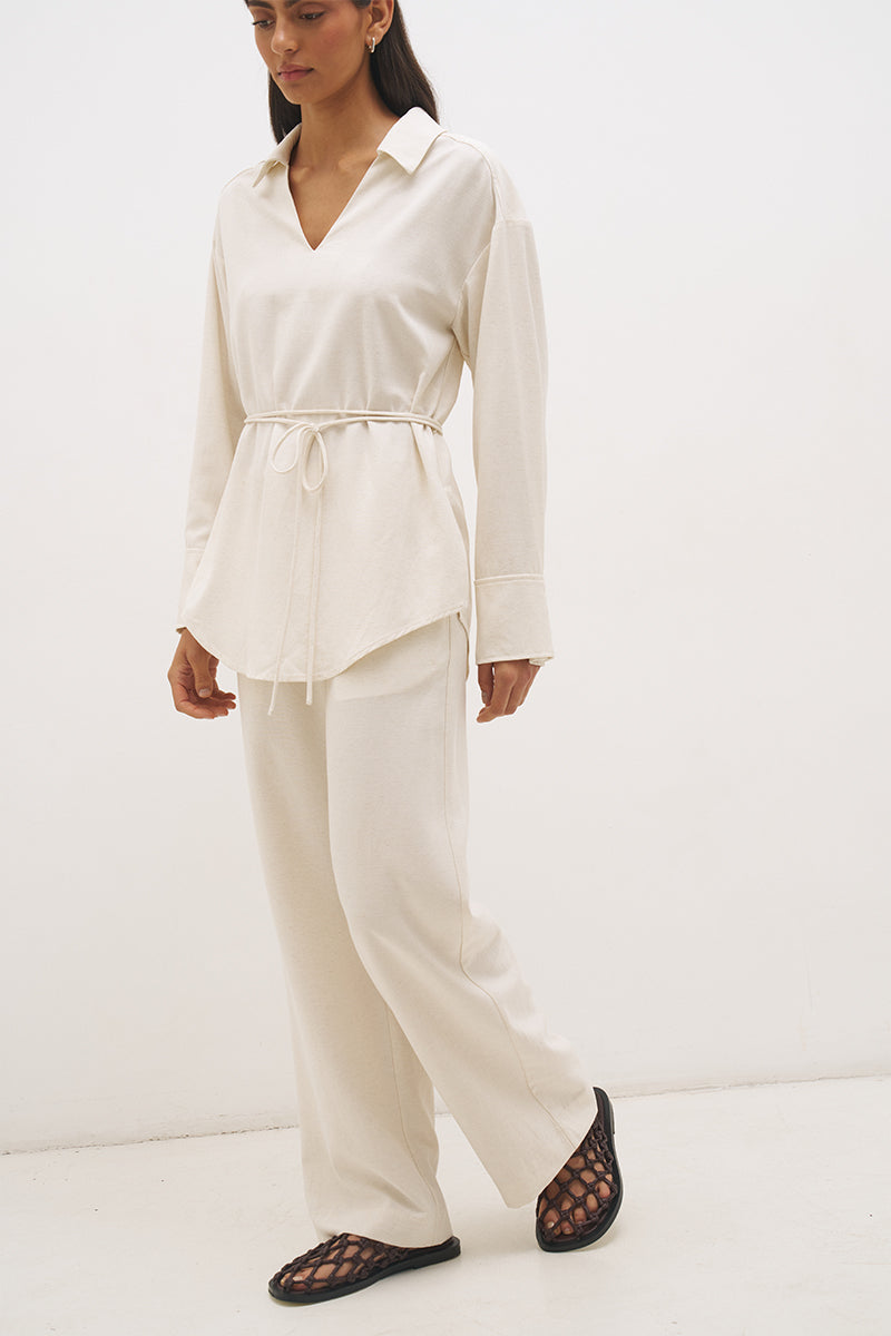 Woman wearing a satin-backed linen blend longline tunic with V neckline, curved hem, relaxed fit, and removable waist tie
