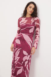 Woman wearing a sheer maxi dress with an exclusive placement print, fit-and-flare silhouette, flared long sleeves, ruched waistline, and a separate full-length slip.