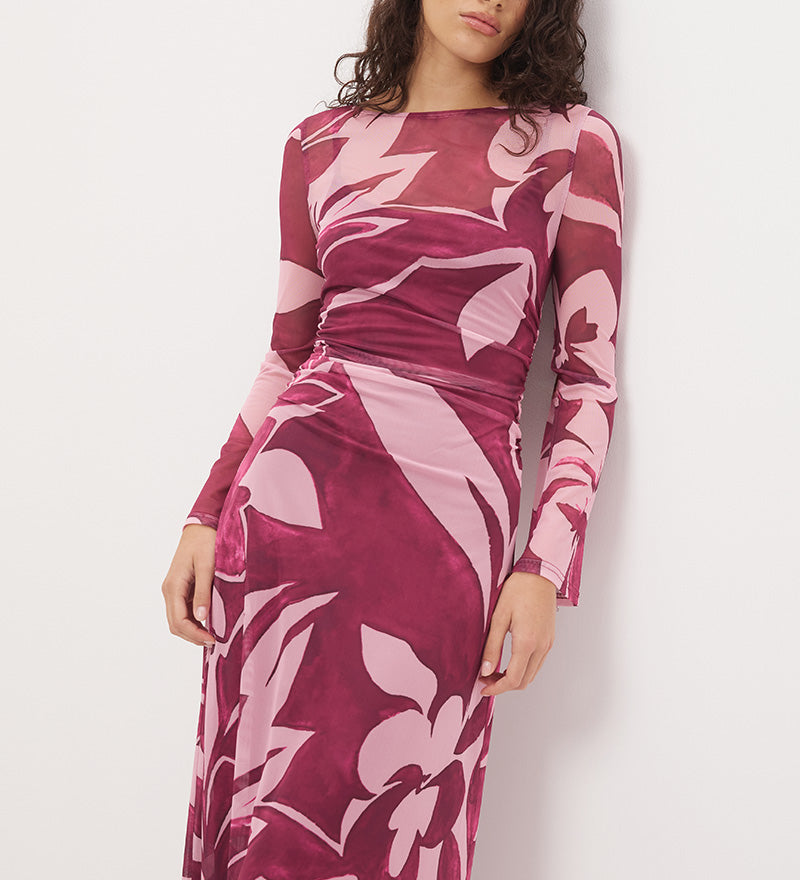 Woman wearing a sheer maxi dress with an exclusive placement print, fit-and-flare silhouette, flared long sleeves, ruched waistline, and a separate full-length slip.