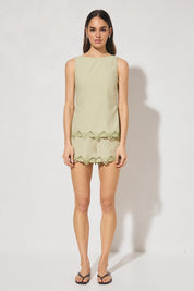 Sleeveless embroidered top with boat neckline, scooped back, functional waist tie, side splits, and relaxed fit