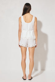 Sleeveless embroidered top with boat neckline, scooped back, functional waist tie, side splits, and relaxed fit