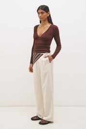 Woman wearing a textured cupro jersey long sleeve top with plunging V neckline, gathered bust detail, empire waist silhouette, and skimming fit