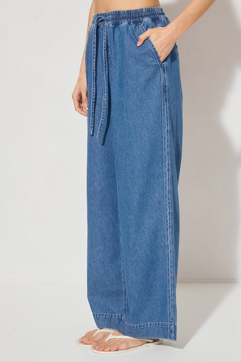 Wide-leg denim jeans with elastic waistband, cornelli piping, slant front pockets, back welt pockets, and heavy topstitching
