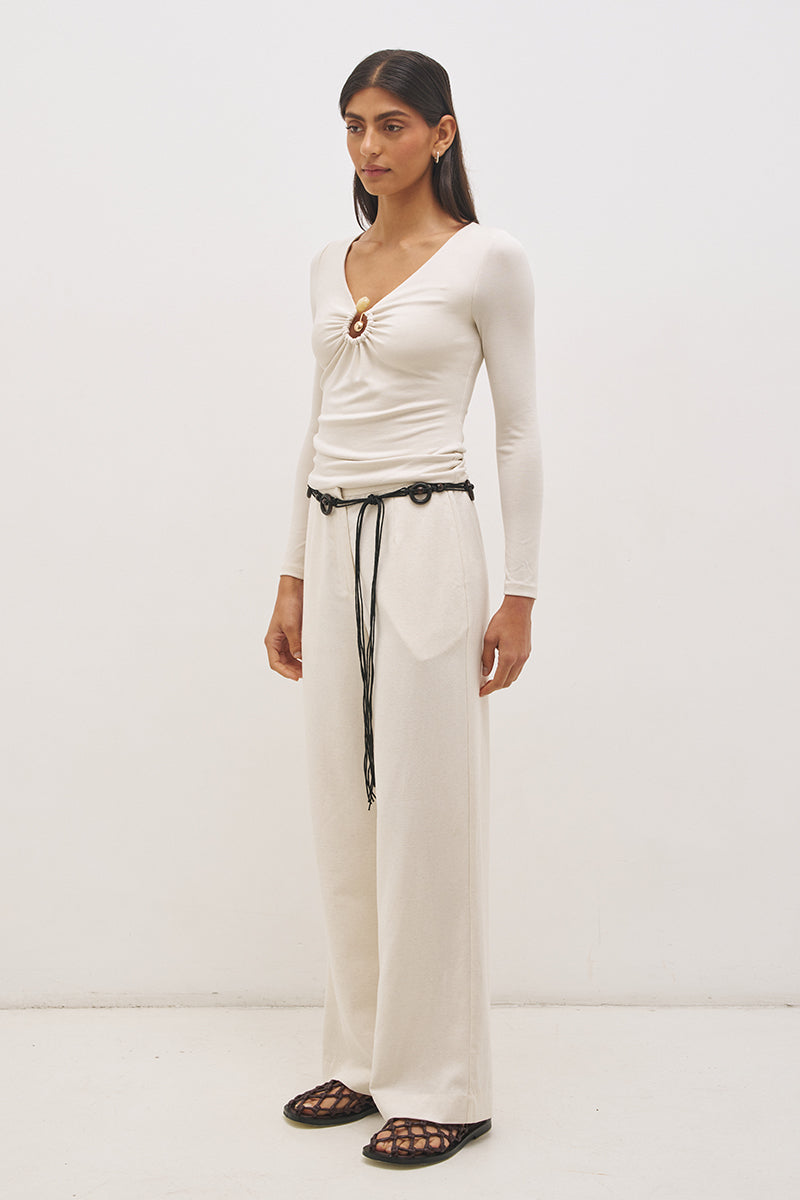 Woman wearing jersey knit long sleeve top with spiral ring neckline, plunging V neck, cascading ruching, and skimming fit silhouette
