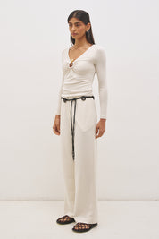 Woman wearing jersey knit long sleeve top with spiral ring neckline, plunging V neck, cascading ruching, and skimming fit silhouette