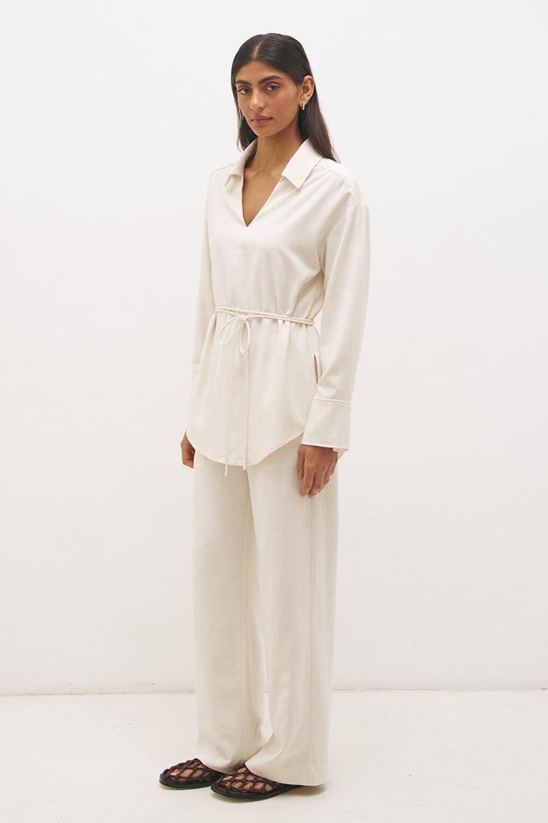 Woman wearing a satin-backed linen blend longline tunic with V neckline, curved hem, relaxed fit, and removable waist tie