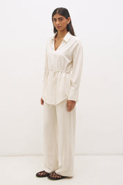 Woman wearing a satin-backed linen blend longline tunic with V neckline, curved hem, relaxed fit, and removable waist tie