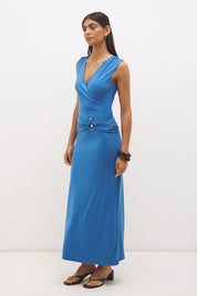 Woman wearing sleeveless jersey knit maxi dress with cowl neckline, spiral ring waist detail, cascading ruching, and fit-and-flare silhouette
