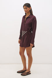 Woman wearing a satin-backed linen blend shirt dress with relaxed fit, collar neckline, curved hem, long sleeves, and removable scarf waist tie