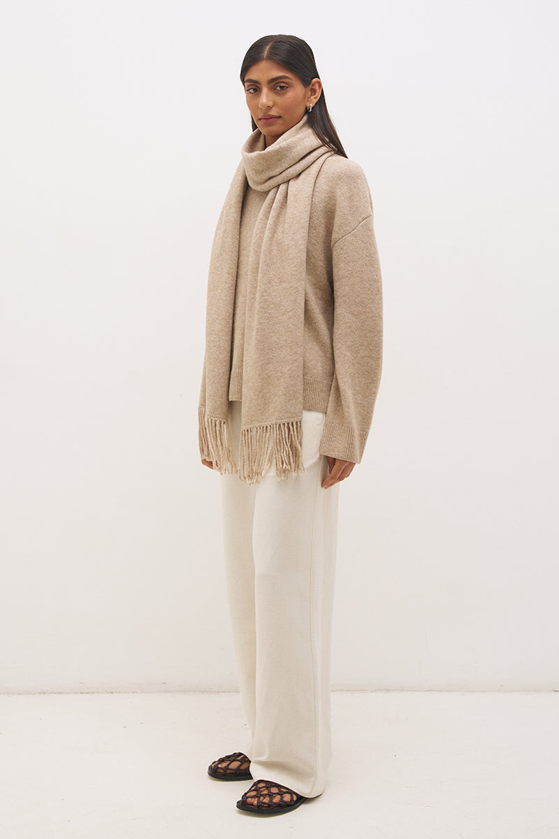 Woman wearing oversized scarf knit jumper with removable tassel scarf, crew neckline, ribbed trims, and relaxed silhouette