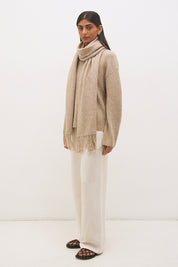Woman wearing oversized scarf knit jumper with removable tassel scarf, crew neckline, ribbed trims, and relaxed silhouette
