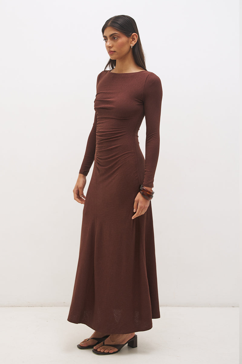 Woman wearing a textured cupro jersey long sleeve midi dress with boat neckline, cascading ruching, fit-and-flare silhouette, and draped A-line hem