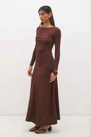 Woman wearing a textured cupro jersey long sleeve midi dress with boat neckline, cascading ruching, fit-and-flare silhouette, and draped A-line hem