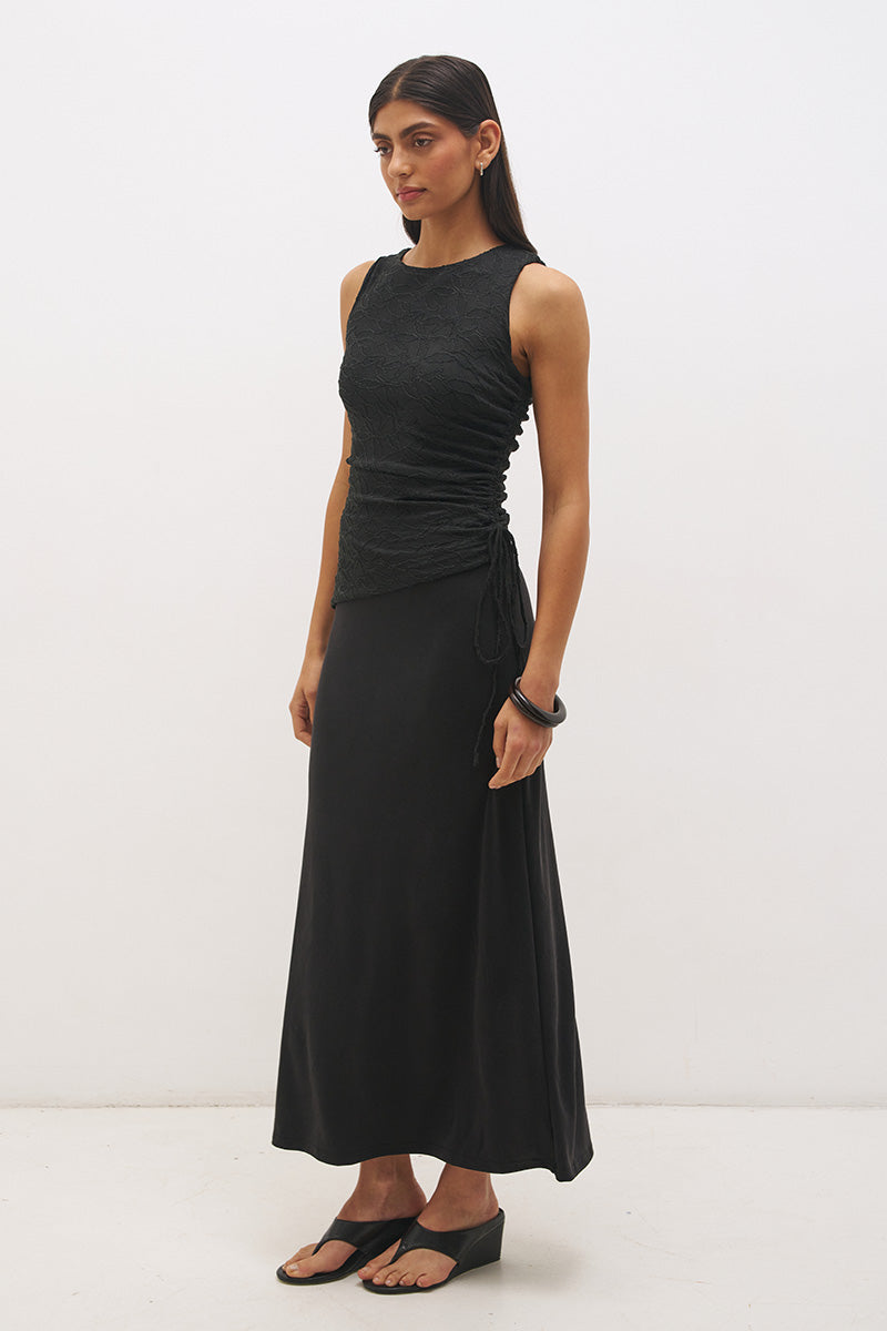 Woman wearing a sleeveless maxi dress with a textured lace bodice overlay, sunray ruching, boat neckline, and a contrast smooth A-line modal skirt in a fit-and-flare silhouette.