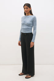 Woman wearing a textured lace long sleeve top with a boat neckline, semi-sheer sleeves, and centre front chest ruching in a skimming fit.