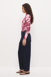 Woman wearing a semi-sheer long sleeve top in stretch ribbed mesh with an exclusive placement print, funnel neckline, centre front chest ruching, and lettuce hem finishes.